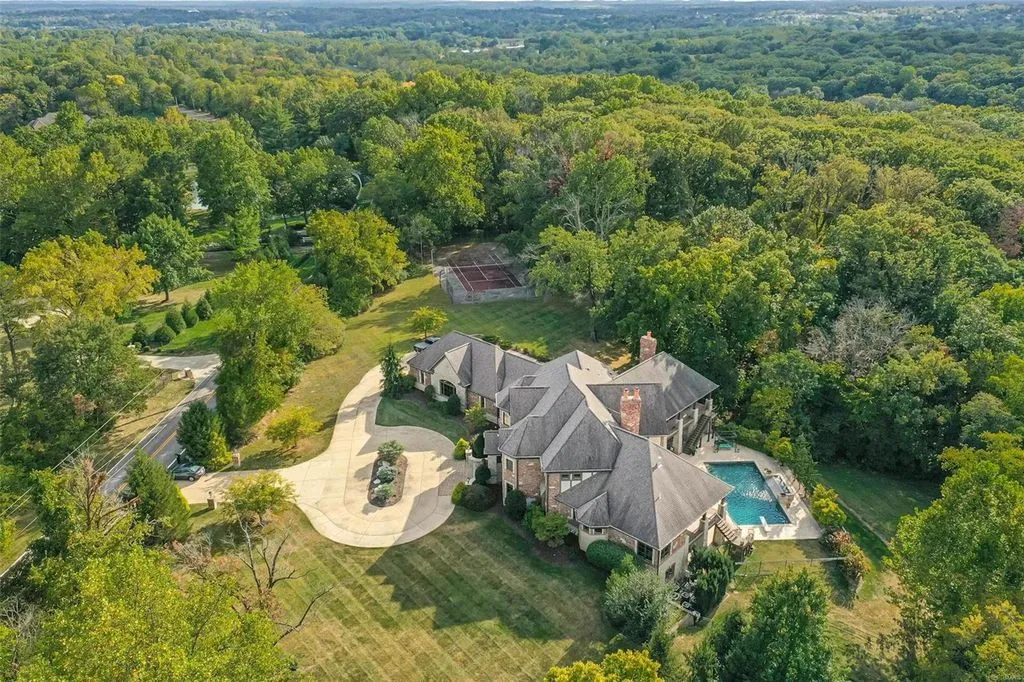 1377 South Mason Road Home in Saint Louis, Missouri. Discover this remarkable 3.3-acre estate bordering Queeny Park, boasting an array of extraordinary outdoor amenities and unmatched privacy. With a massive 2-story foyer, designer kitchen, primary suite with a see-through fireplace, and a sprawling lower level featuring a rec room, theatre, gym, and more. 