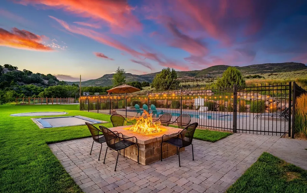 4115 Greener Hills Drive Home in Heber, Utah. Discover a 7.55-acre gated estate in Greener Hills. This luxury property features remarkable entertainment amenities, from exposed wood beams to a gourmet kitchen with Wolf appliances, an outdoor kitchen, pool, and firepit. The main level master offers radiant heat flooring, and the estate includes a playhouse, home theater, and more.