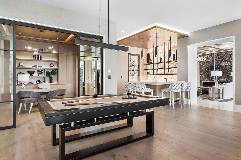 Indulge in the epitome of waterfront luxury at this 10,784-square-foot estate in Royal Palm Yacht & Country Club. Crafted by Wietsma Lippolis Construction, this masterpiece boasts six bedroom suites, expansive living areas curated by Artisan Interiors, and cutting-edge Crestron home technology.