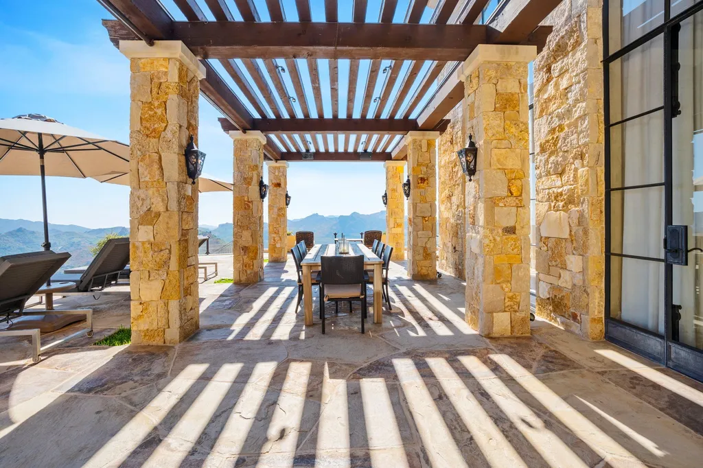 340 North Kanan Dume Road Home in Malibu, California. Perched atop a Malibu Canyon peak, the majestic Malibu Rocky Oaks is a stone-clad Tuscan villa offering unrivaled luxury and panoramic views. This 9,000-square-foot estate boasts 37 picturesque acres, a renowned vineyard, and endless world-class amenities. With a private helipad and infinity pool, this masterpiece redefines the essence of luxury living in the Malibu hills.