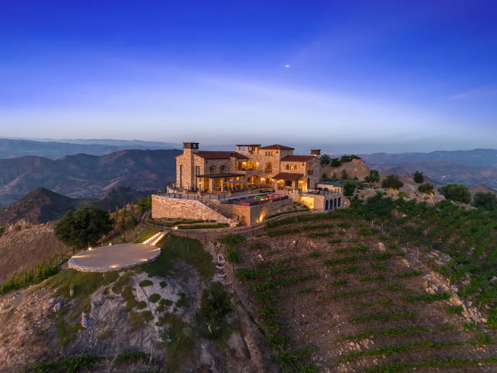 340 North Kanan Dume Road Home in Malibu, California. Perched atop a Malibu Canyon peak, the majestic Malibu Rocky Oaks is a stone-clad Tuscan villa offering unrivaled luxury and panoramic views. This 9,000-square-foot estate boasts 37 picturesque acres, a renowned vineyard, and endless world-class amenities. With a private helipad and infinity pool, this masterpiece redefines the essence of luxury living in the Malibu hills.