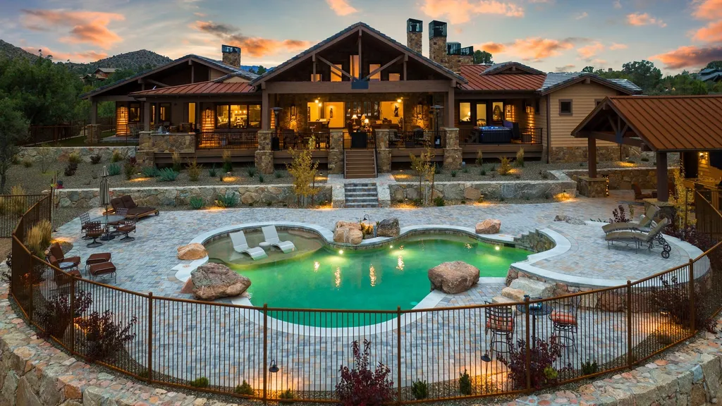 4971 West Three Forks Road Home in Prescott, Arizona. Explore the epitome of luxury living in this privately gated ranch compound with unobstructed views. This 4-bedroom, 5,555 sq.ft home features a 7-car garage, attached guest quarters, private pool with cabana, wet bar, and a 20 ft indoor-outdoor panoramic glass wall door.