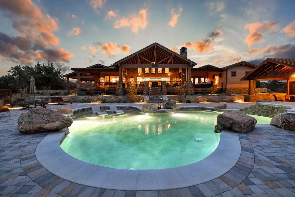 4971 West Three Forks Road Home in Prescott, Arizona. Explore the epitome of luxury living in this privately gated ranch compound with unobstructed views. This 4-bedroom, 5,555 sq.ft home features a 7-car garage, attached guest quarters, private pool with cabana, wet bar, and a 20 ft indoor-outdoor panoramic glass wall door.