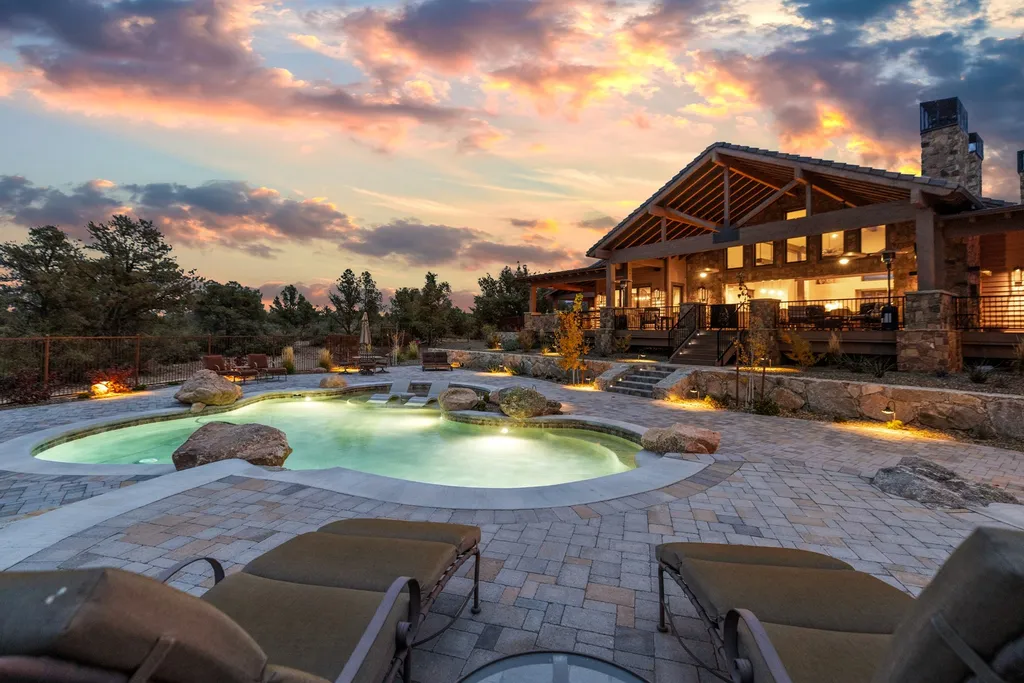 4971 West Three Forks Road Home in Prescott, Arizona. Explore the epitome of luxury living in this privately gated ranch compound with unobstructed views. This 4-bedroom, 5,555 sq.ft home features a 7-car garage, attached guest quarters, private pool with cabana, wet bar, and a 20 ft indoor-outdoor panoramic glass wall door.