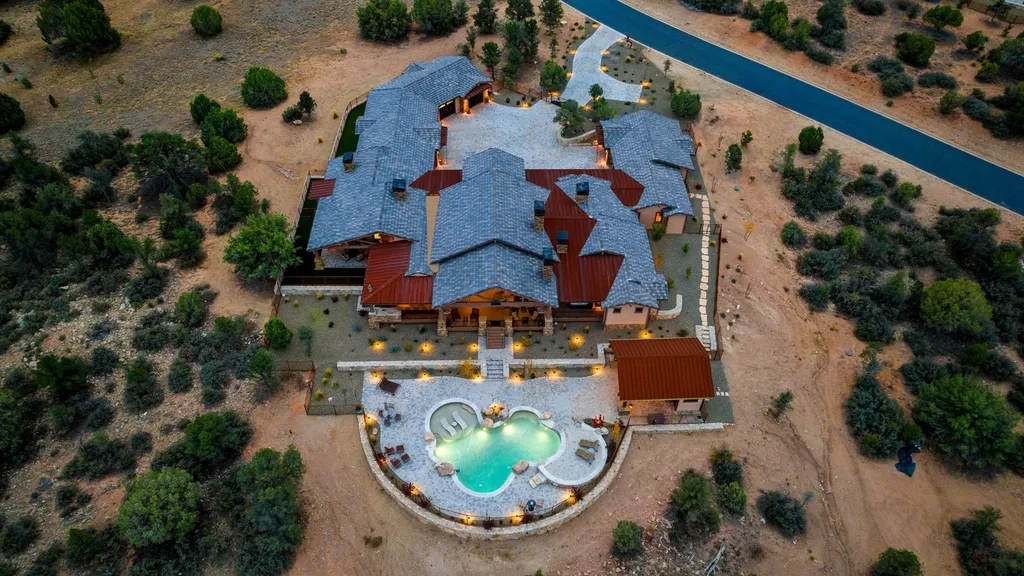 4971 West Three Forks Road Home in Prescott, Arizona. Explore the epitome of luxury living in this privately gated ranch compound with unobstructed views. This 4-bedroom, 5,555 sq.ft home features a 7-car garage, attached guest quarters, private pool with cabana, wet bar, and a 20 ft indoor-outdoor panoramic glass wall door.