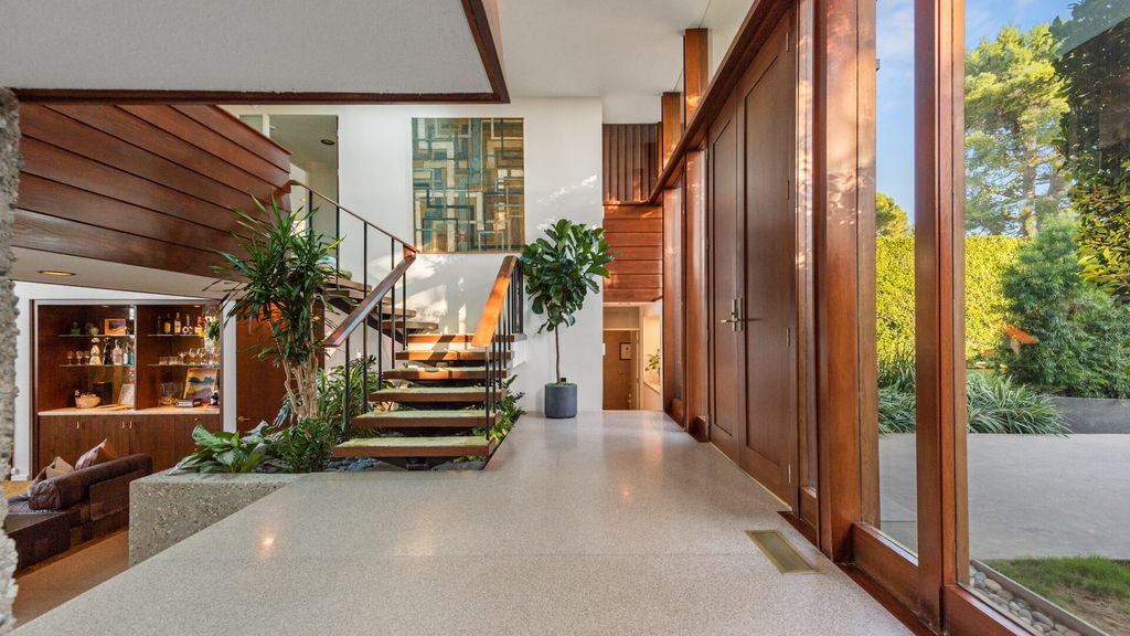 1875 Carla Ridge Home in Beverly Hills, California. Behold an architectural masterpiece designed by Rex Lotery in 1965—a stunning Mid-Century home crafted with concrete, wood, glass, and stone. This rare gem stands out as one of only a handful of two-story homes in the coveted Trousdale neighborhood, and it has recently undergone a meticulous renovation to enhance its timeless allure.