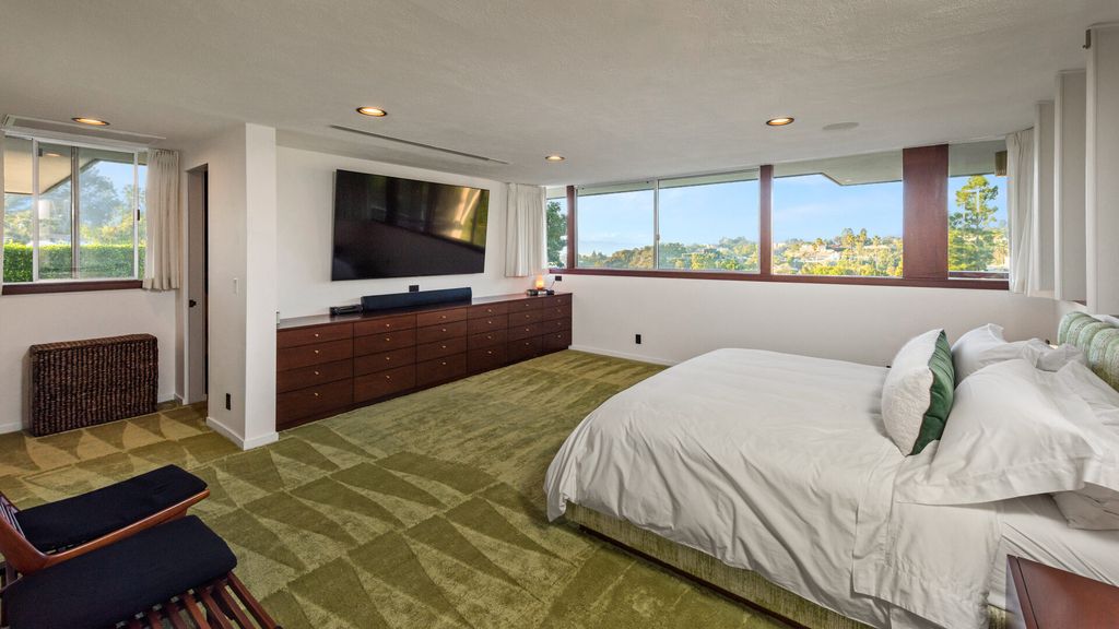 1875 Carla Ridge Home in Beverly Hills, California. Behold an architectural masterpiece designed by Rex Lotery in 1965—a stunning Mid-Century home crafted with concrete, wood, glass, and stone. This rare gem stands out as one of only a handful of two-story homes in the coveted Trousdale neighborhood, and it has recently undergone a meticulous renovation to enhance its timeless allure.