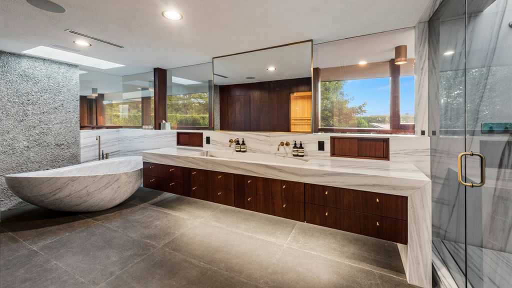 1875 Carla Ridge Home in Beverly Hills, California. Behold an architectural masterpiece designed by Rex Lotery in 1965—a stunning Mid-Century home crafted with concrete, wood, glass, and stone. This rare gem stands out as one of only a handful of two-story homes in the coveted Trousdale neighborhood, and it has recently undergone a meticulous renovation to enhance its timeless allure.