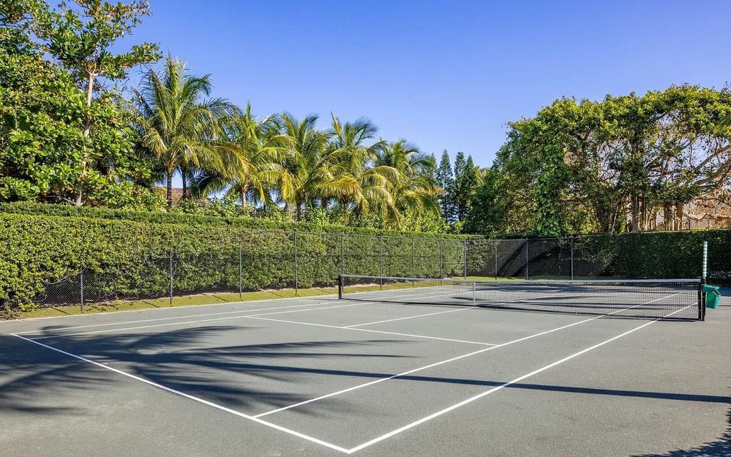 Nestled in Palm Beach's prestigious Estate Section, this 1.3+/- acre property epitomizes luxury living with a stunning clay tennis court, two guest houses, and immaculate grounds. A gated entry leads to a circular drive and ample parking, complemented by a separate service area and a 2-car garage.
