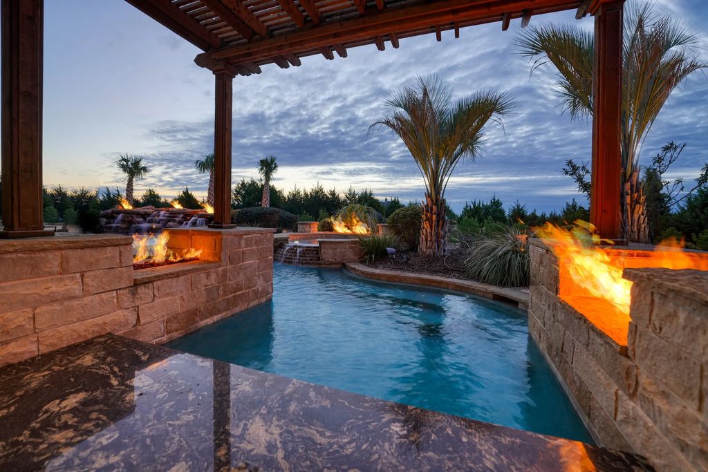 1252 Wales Drive Home in Rockwall, Texas. Step into luxury living at its finest with this illustrious estate set on over two private acres. Enjoy resort-style amenities including a pool with swim-up bar, fire features, waterfalls, and a covered patio with motorized screens.
