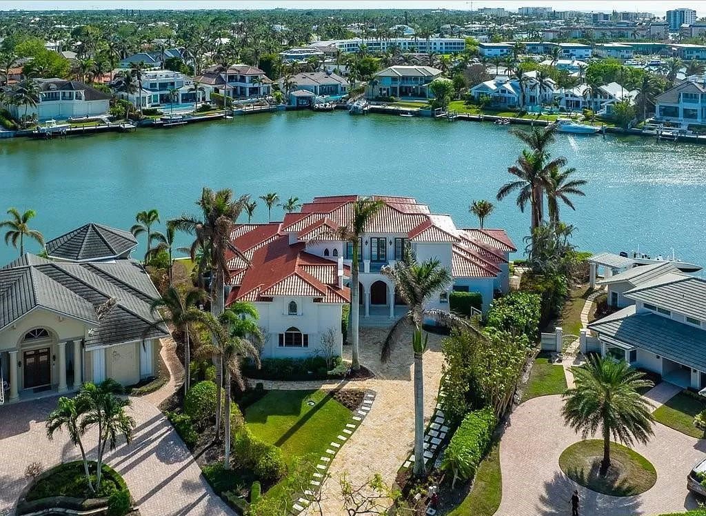 Indulge in the epitome of luxury waterfront living at this magnificent Naples estate on 210 Cuddy Ct. Crafted by Kurtz Homes, this opulent residence boasts grand columns, exquisite tile flooring, and coffered ceilings, flooded with natural light.