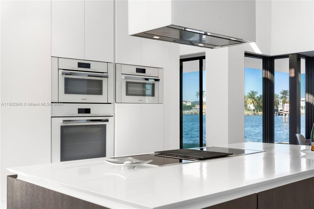 Discover unparalleled luxury in this modern masterpiece on guard-gated Biscayne Point Island. This exquisitely renovated home offers wide bay sunset views from a private peninsula with 360 feet of water frontage.