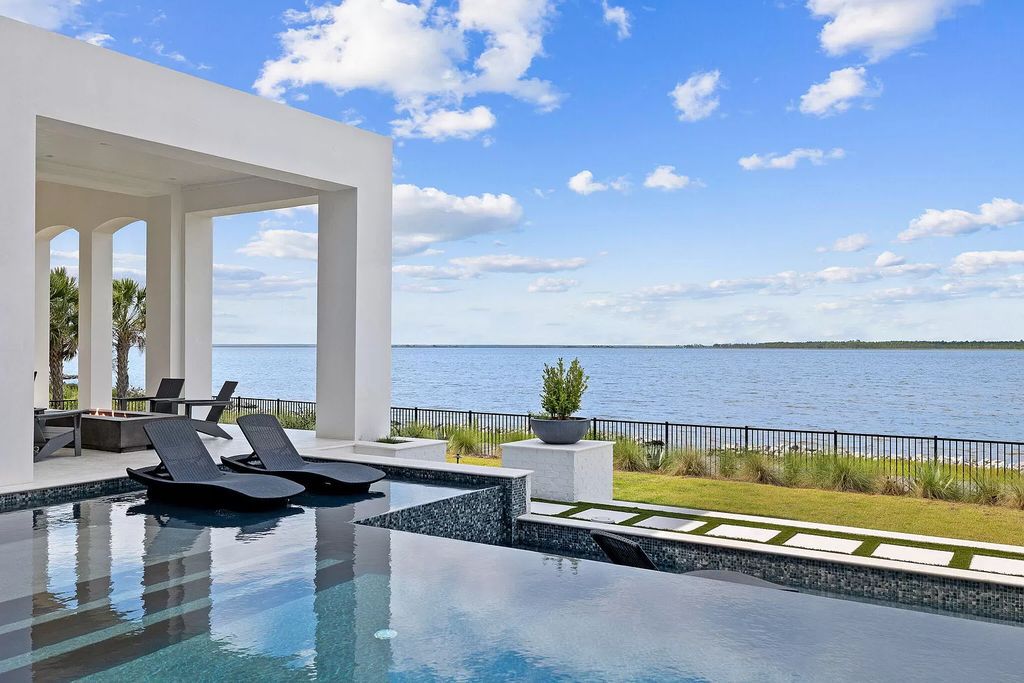 Nestled on a double homesite with 150'+ of Choctawhatchee Bay frontage in the prestigious gated enclave of Churchill Oaks, 51 Junop Court is a stunning legacy residence designed by Matt Savois and built by Grand Bay Construction.