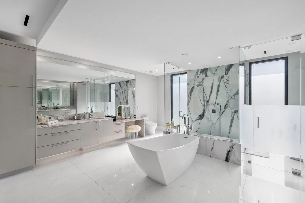 This 5-bed, 7-bath masterpiece, built in 2021, spans over 6,159 sq ft on a 0.30-acre lot. Highlights include a 2-story great room with stunning glass walls and a gas fireplace, a formal dining room with a glass wine closet, a custom kitchen with double-thick quartzite countertops, Miele appliances, and Carrara porcelain tiles.
