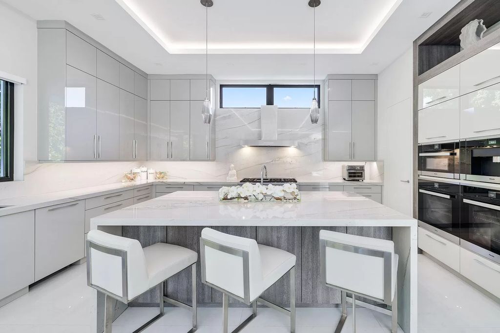 This 5-bed, 7-bath masterpiece, built in 2021, spans over 6,159 sq ft on a 0.30-acre lot. Highlights include a 2-story great room with stunning glass walls and a gas fireplace, a formal dining room with a glass wine closet, a custom kitchen with double-thick quartzite countertops, Miele appliances, and Carrara porcelain tiles.