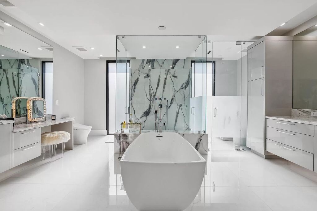 This 5-bed, 7-bath masterpiece, built in 2021, spans over 6,159 sq ft on a 0.30-acre lot. Highlights include a 2-story great room with stunning glass walls and a gas fireplace, a formal dining room with a glass wine closet, a custom kitchen with double-thick quartzite countertops, Miele appliances, and Carrara porcelain tiles.