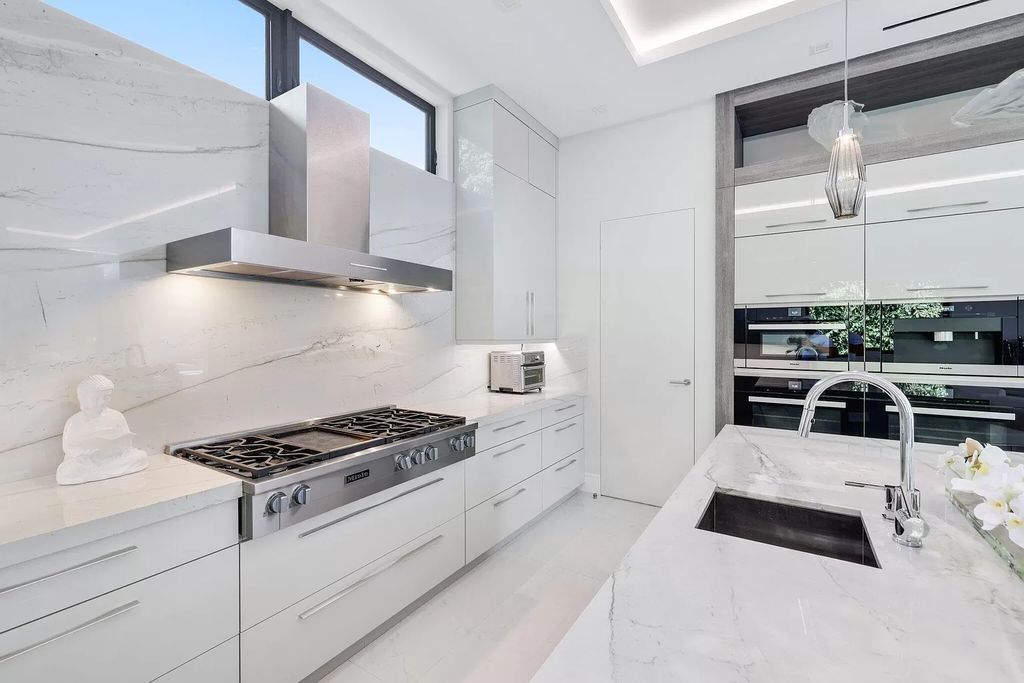 This 5-bed, 7-bath masterpiece, built in 2021, spans over 6,159 sq ft on a 0.30-acre lot. Highlights include a 2-story great room with stunning glass walls and a gas fireplace, a formal dining room with a glass wine closet, a custom kitchen with double-thick quartzite countertops, Miele appliances, and Carrara porcelain tiles.