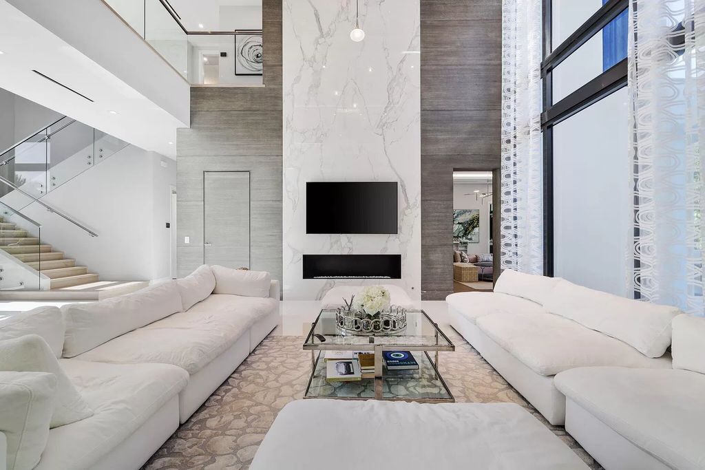 This 5-bed, 7-bath masterpiece, built in 2021, spans over 6,159 sq ft on a 0.30-acre lot. Highlights include a 2-story great room with stunning glass walls and a gas fireplace, a formal dining room with a glass wine closet, a custom kitchen with double-thick quartzite countertops, Miele appliances, and Carrara porcelain tiles.