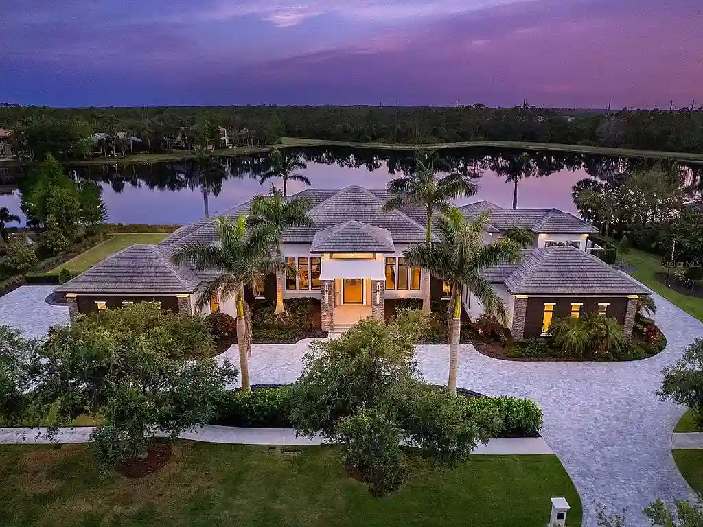 Front view of the stunning $7.5M custom lakefront estate at 18826 Ganton Ave in The Concession, Bradenton, showcasing grand circular driveway and elegant stone columns.