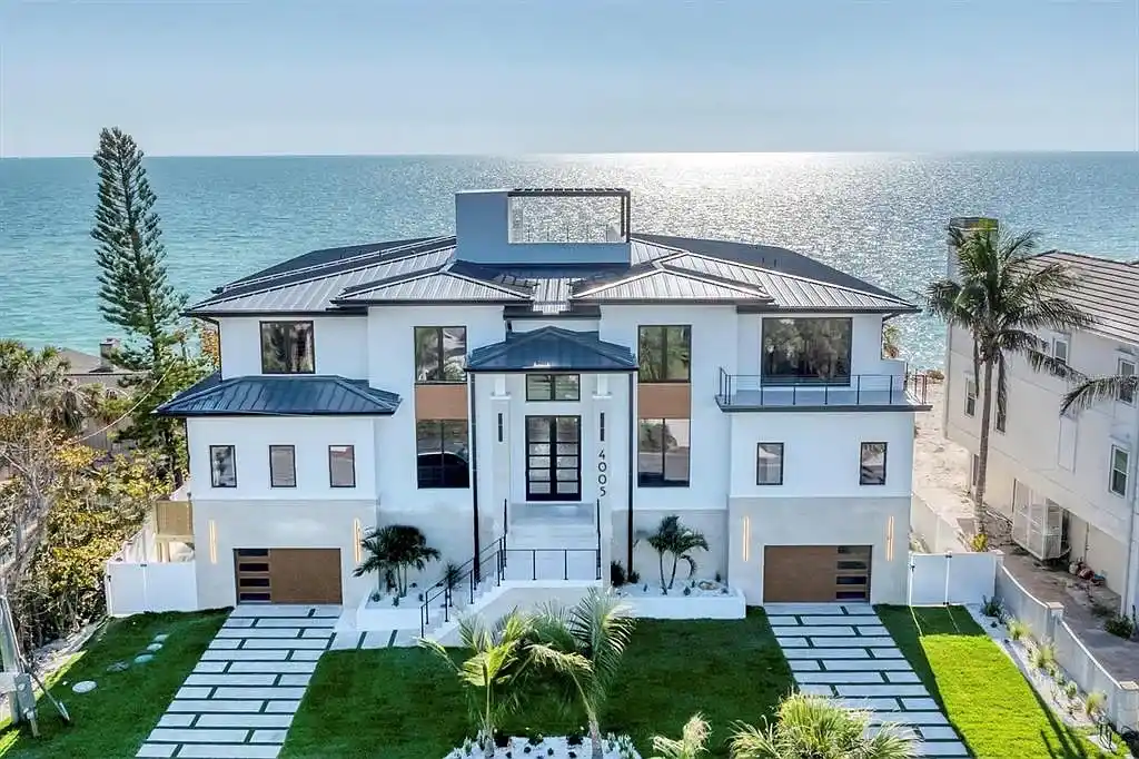 Exterior view of 4005 Casey Key Rd, a $11.9 million modern Gulf-front estate in Nokomis, Florida, featuring a rooftop terrace, oceanfront pool, and lush tropical landscaping