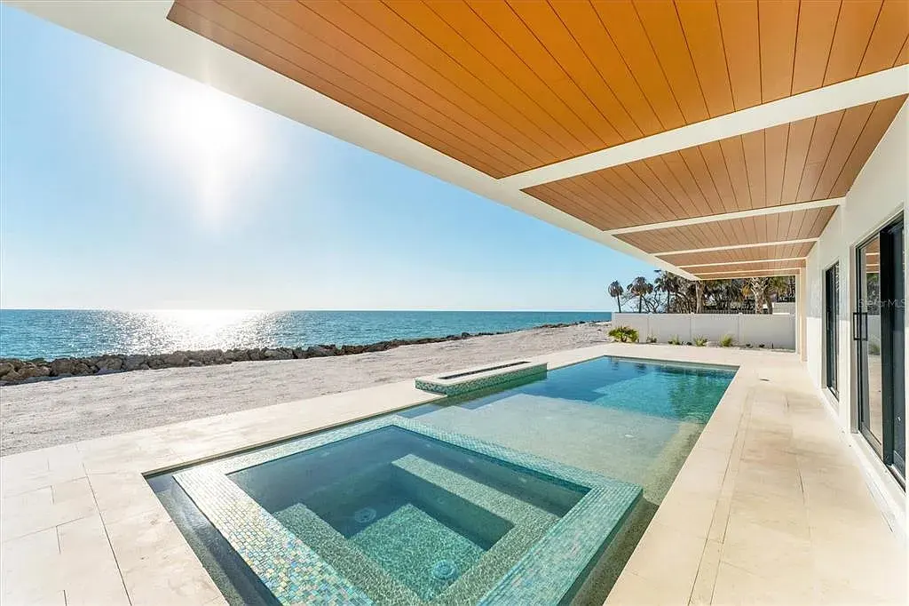 Exterior view of 4005 Casey Key Rd, a $11.9 million modern Gulf-front estate in Nokomis, Florida, featuring a rooftop terrace, oceanfront pool, and lush tropical landscaping