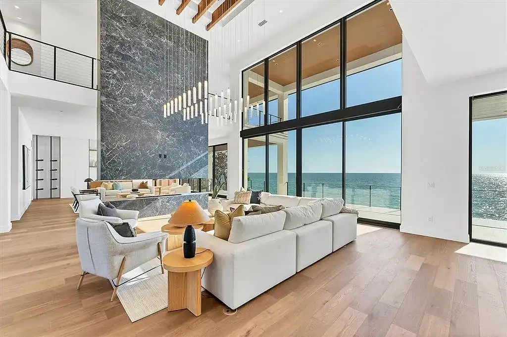 Exterior view of 4005 Casey Key Rd, a $11.9 million modern Gulf-front estate in Nokomis, Florida, featuring a rooftop terrace, oceanfront pool, and lush tropical landscaping
