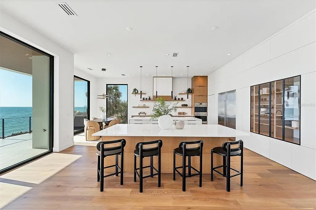 Exterior view of 4005 Casey Key Rd, a $11.9 million modern Gulf-front estate in Nokomis, Florida, featuring a rooftop terrace, oceanfront pool, and lush tropical landscaping