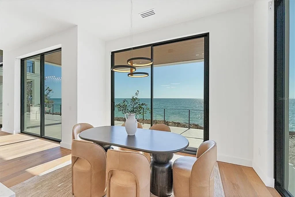 Exterior view of 4005 Casey Key Rd, a $11.9 million modern Gulf-front estate in Nokomis, Florida, featuring a rooftop terrace, oceanfront pool, and lush tropical landscaping