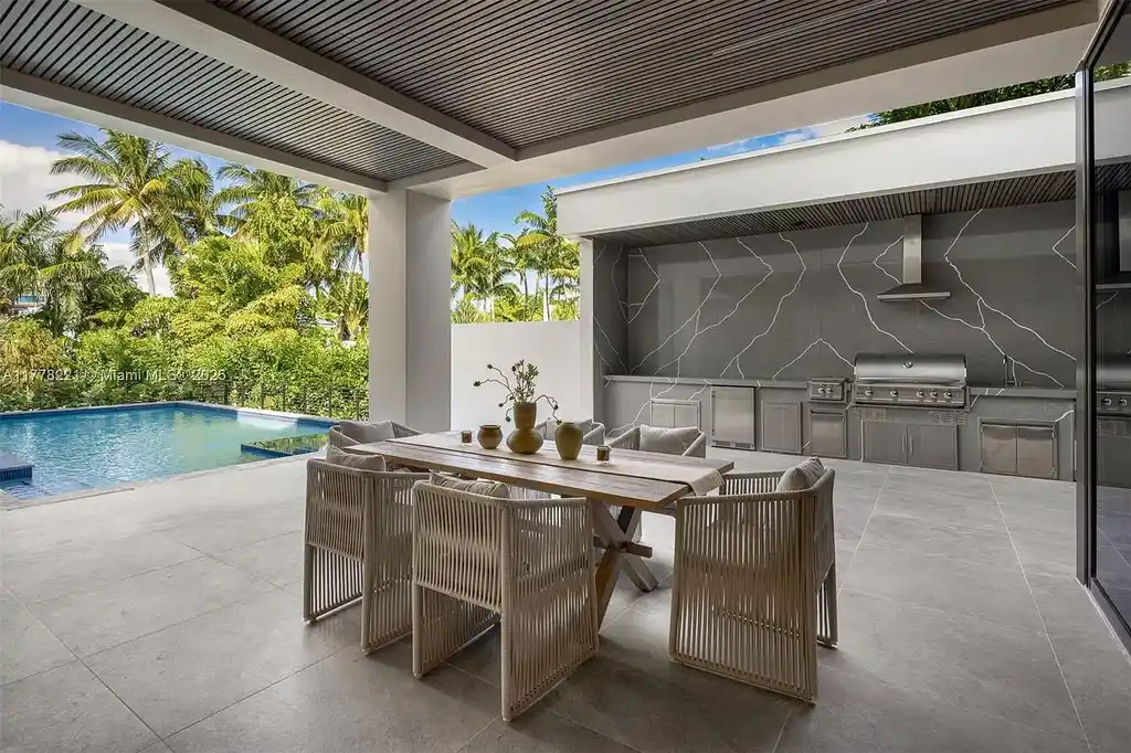 Luxury waterfront home at 725 NE 77th St, Miami featuring private dock, heated pool, modern architecture, and lush landscaping in Belle Meade