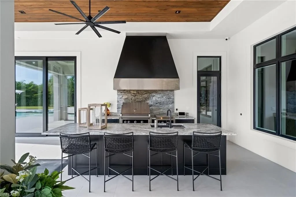 Luxury estate at 115 East Ave in Naples featuring outdoor kitchen, screened lanai, fire pit, and heated saltwater pool within Pine Ridge Estates