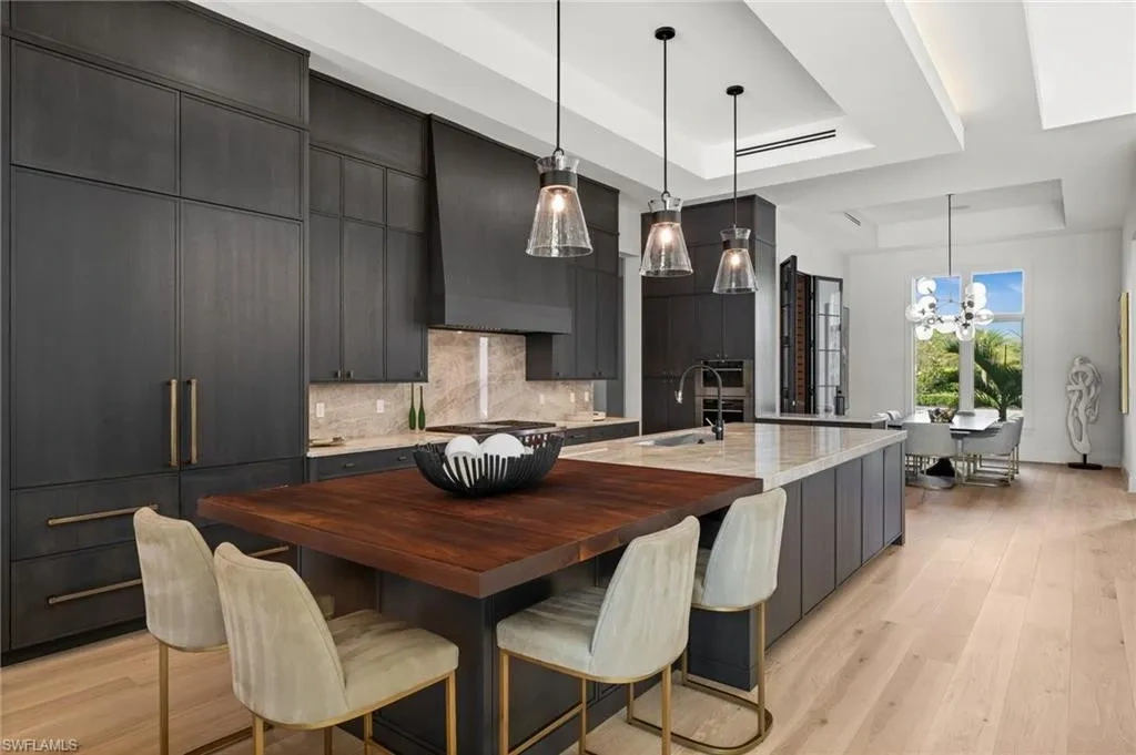 Luxury estate at 115 East Ave in Naples featuring outdoor kitchen, screened lanai, fire pit, and heated saltwater pool within Pine Ridge Estates