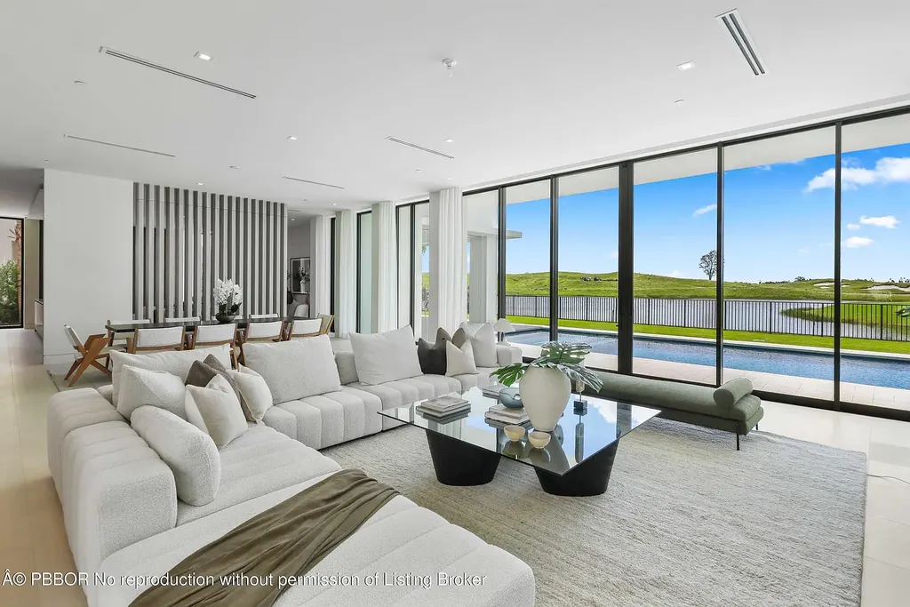 Front view of 10967 Monte Rosa Dr in Palm Beach Gardens, a $9.6 million modern golf estate by architect Max Strang featuring glass facades, terraces, and lake views.