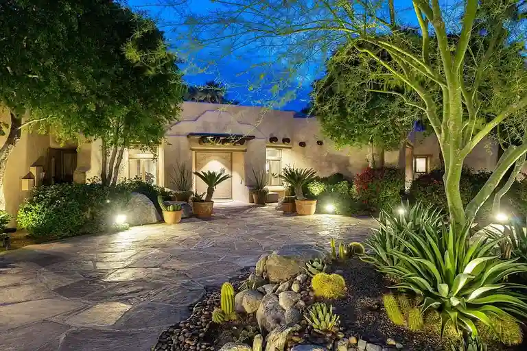 The illuminated entryway and driveway of 475 S Via Las Palmas at night, featuring desert landscaping, cactuses, and accent lighting, showcasing the estate’s elegant curb appeal.