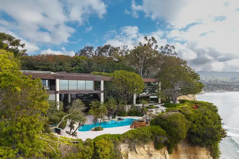 The Edward R. Niles designed residence perched dramatically on the Point Dume bluffs, showing the exterior, pool, and ocean views of this Most Expensive Home in Malibu.