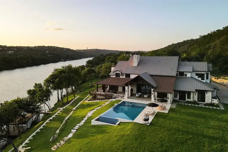The front exterior of a modern luxury Austin home featuring extensive glass walls, vertical wooden slats, and large cantilevered sections, setting it apart as an **expensive home in Austin**
