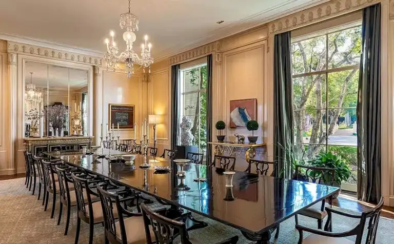 Formal dining room with capacity for over 20 guests, black lacquer table, crystal chandelier, and large windows overlooking the estate.