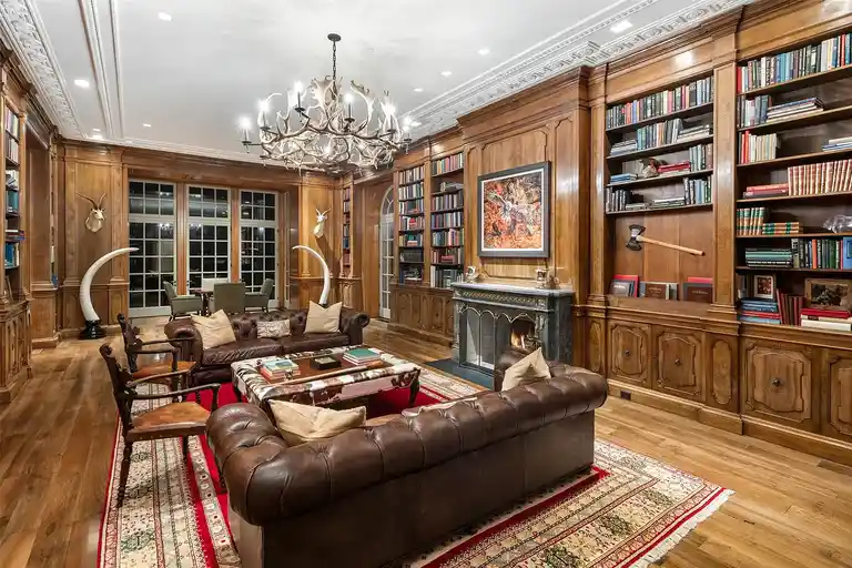 Elegant wood-paneled library inside the most expensive home in Texas with chandeliers and sofas.