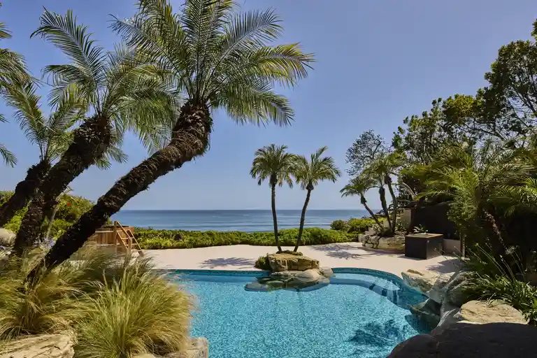 The outdoor swimming pool area facing the Pacific Ocean at 6962 Wildlife Rd, The Carson Legacy Estate, currently the Most Expensive Home in Malibu.