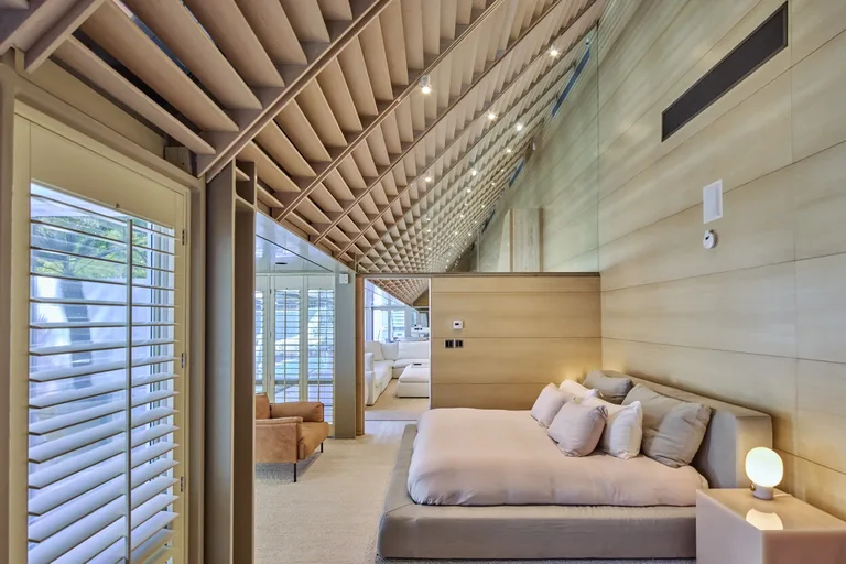 Interior of the Primary Suite bedroom featuring a high vaulted wood-slat ceiling, open space, and a neutral color palette, at 6962 Wildlife Rd.