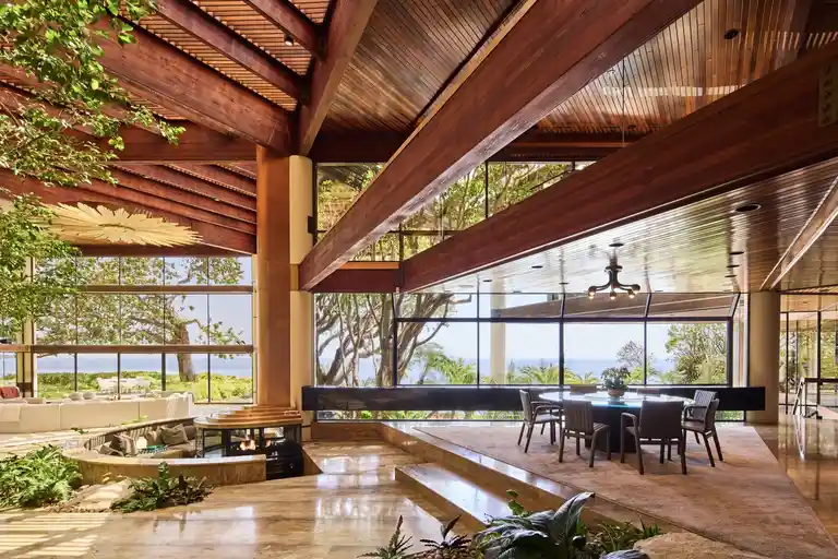 Interior view of the dining area and the sunken fireplace, featuring marble, wood, and panoramic ocean views inside the Most Expensive Home in Malibu.
