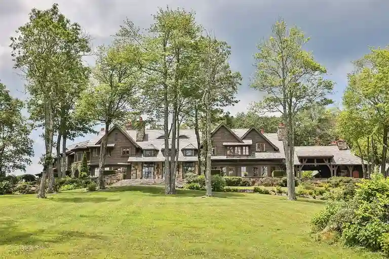 Main facade of Sagee Manor, the most expensive house in North Carolina, showcasing the rustic stone and wood architecture with a vast front lawn on the mountaintop estate