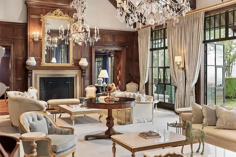 Elegant living room interior of Sagee Manor, the **most expensive house in North Carolina**, featuring exquisite wood paneling, ornate chandeliers, a grand fireplace, and abundant natural light.