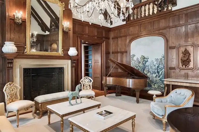 Grand living area in Sagee Manor, the most expensive house in north carolina, with a carved stone fireplace, baby grand piano, and luxury seating.