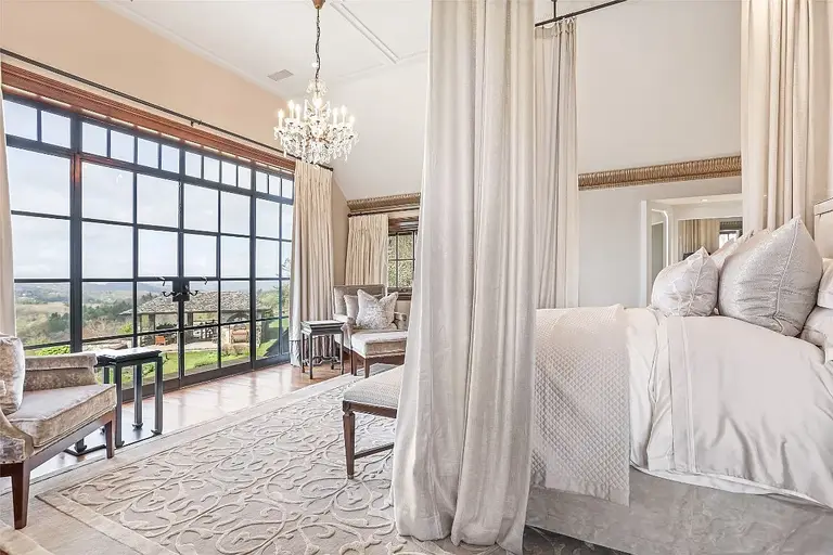Luxury master bedroom in Sagee Manor, the most expensive house in north carolina, with large windows offering panoramic views, a chandelier, and elegant drapery.