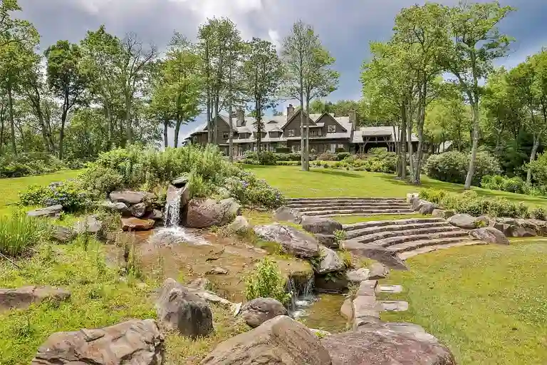 Outdoor tiered amphitheater at Sagee Manor, the **most expensive house in north carolina**, featuring a natural stream with a small waterfall, leading up to the rustic lodge-style main house.
