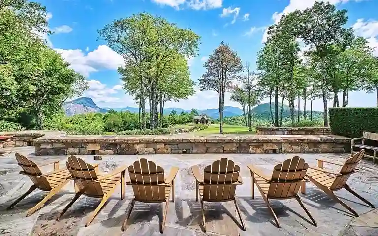 Outdoor stone patio at Sagee Manor, the **most expensive house in North Carolina**, with Adirondack chairs, a fire pit, and panoramic views of the Blue Ridge Mountains.