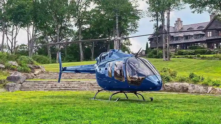 A blue private helicopter on the helipad at Sagee Manor, the **most expensive house in North Carolina**, with the expansive main manor visible in the background