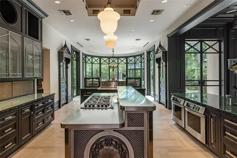 Commercial-grade gourmet kitchen in The Lodge, the **most expensive home in Houston**, featuring black cabinetry, stainless steel island, high-end double ovens, and large arched windows