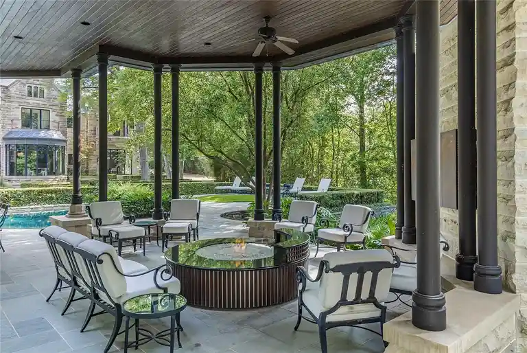 Covered outdoor patio with a luxury fire pit and seating area next to the pool at The Lodge, the **most expensive home in Houston**, offering private outdoor entertaining space