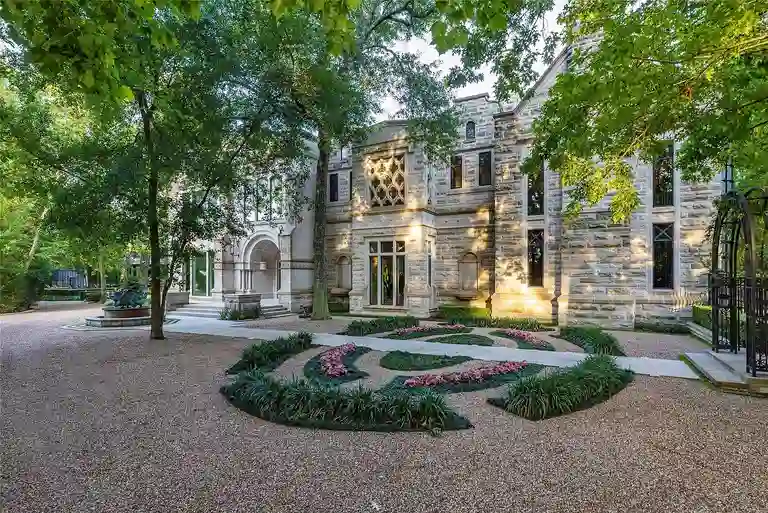 Main facade of The Lodge at Hunters Creek, the most expensive home in Houston, showing Indiana limestone details, intricate windows, and formal gardens.